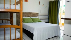 A room with a bunk bed, a single bed with green pillows, a wooden headboard, a white wall with a small artwork, and a green curtain. - Recanto Soga Chalés (Ubatuba)