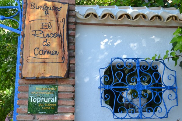 A wooden signboard with text, a metal gate, and a window with decorative ironwork. - Loft type, pool, terrace, wifi, mountain views, sunsets. (Rute)