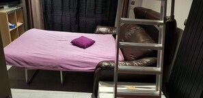 Una habitación pequeña con cama, una mesita y un armario.