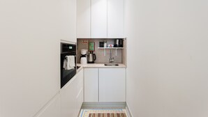 A compact kitchen with white cabinets, a coffee maker, a kettle, and a sink. - FLH Bacalhoeiros Charming Place (Lisbon)
