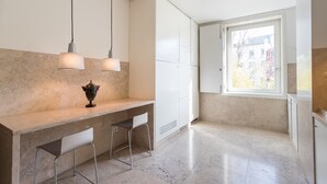 A modern kitchen with a marble countertop, two pendant lights, a vase, and a window with a view of buildings. - FLH Chiado Design Flat (Lisbon)