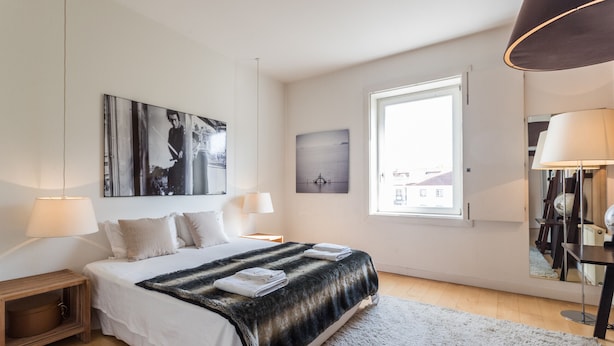 A modern bedroom with a large bed, two bedside tables, a window, and artwork on the walls. - FLH Chiado Design Flat (Lisbon)