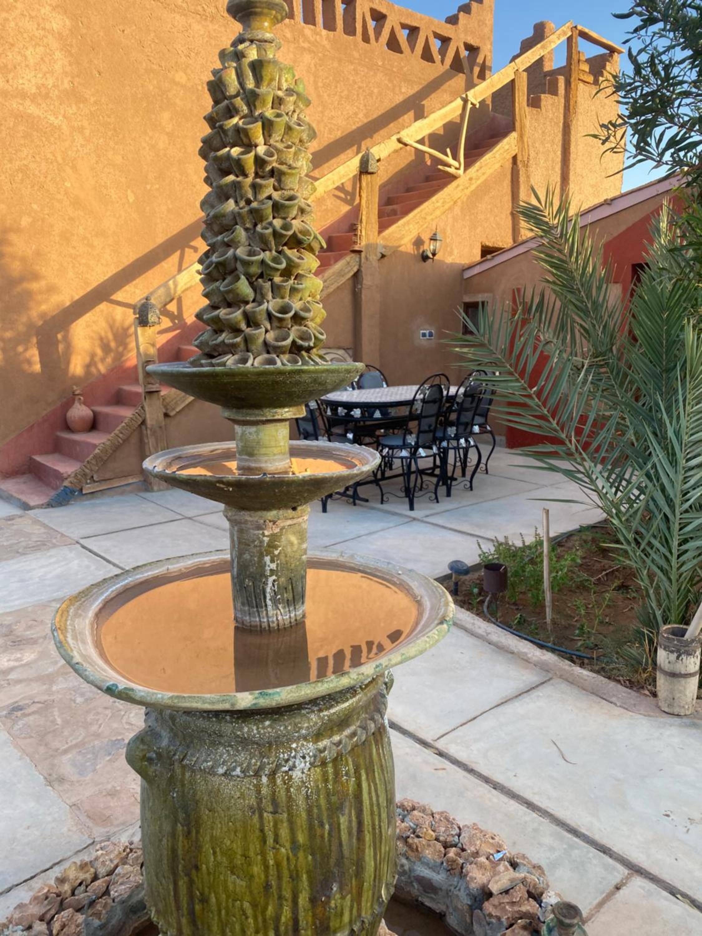 A traditional fountain with multiple tiers and a staircase in the background.
