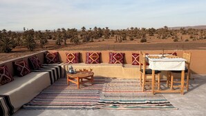 A rooftop terrace with a seating area, a table, and chairs. - Dar Talmoudi (Tagounite)