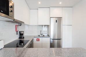 A modern kitchen with a stainless steel refrigerator, a coffee maker, and a sink.