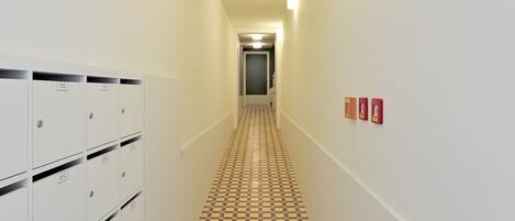 A hallway with lockers, a checkered floor, and emergency exit signs.