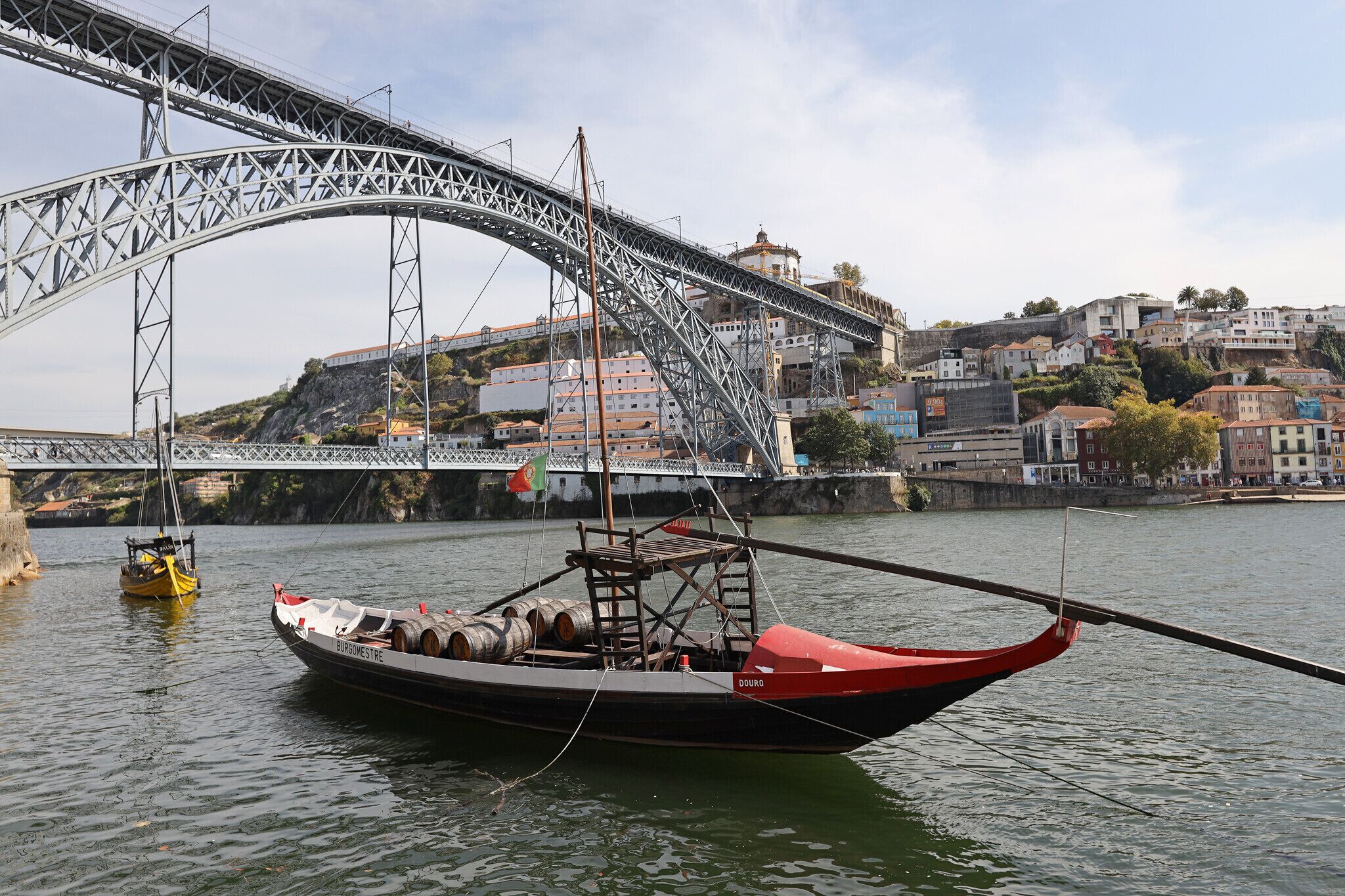 A boat docked near a bridge with a cityscape in the background.