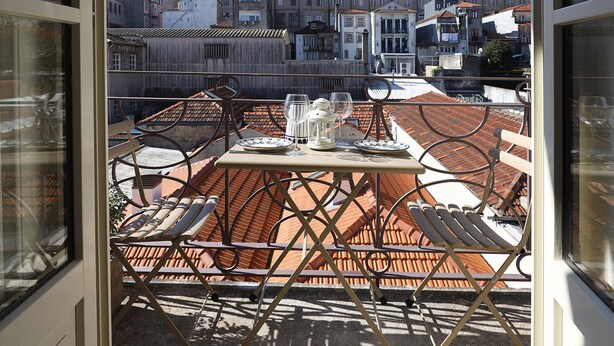 A terrace with a table set for dining, a chair, and a view of the cityscape. - FLH Almada Cozy Apartment with View (Oporto)