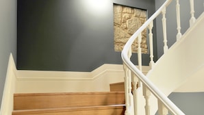 A wooden staircase with white balusters and a stone accent wall. - FLH Almada Cozy Apartment with View (Oporto)