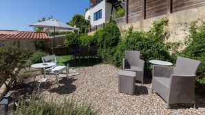 An outdoor patio with wicker furniture, a table, and an umbrella. - FLH Castle Duplex with Terrace (Lisbon)