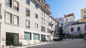 Vista d'un carrer amb un edifici que destaca per una gran porta de vidre, un camió estacionat i una escala que condueix a un nivell superior.
