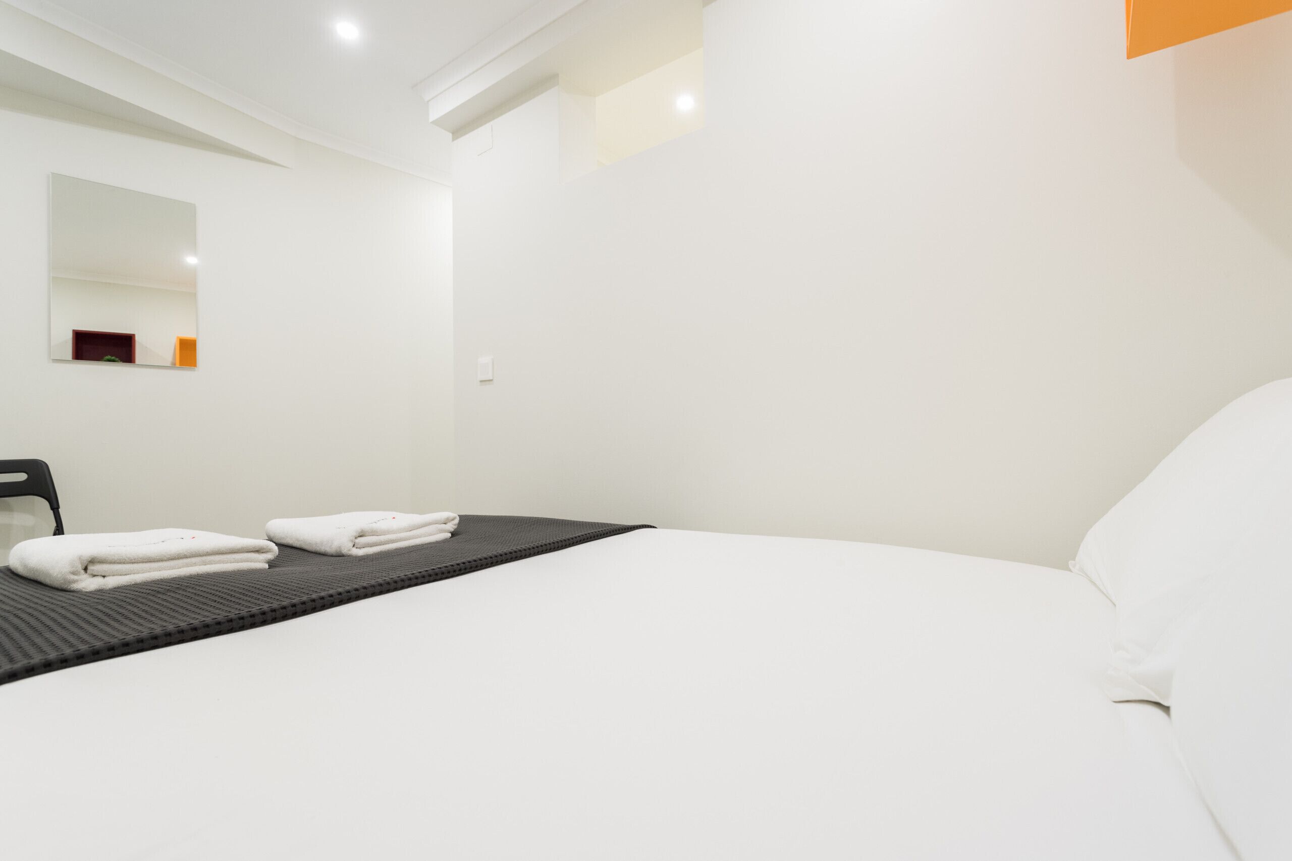 A modern hotel room with a large bed, a black mat, and neatly folded white towels.