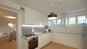 Una cocina moderna con armarios blancos, horno empotrado, microondas y una lámpara colgante.