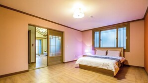 A bedroom with a large bed, a mirror, and a sliding door leading to another room. - Hue travel Pension (Muan)