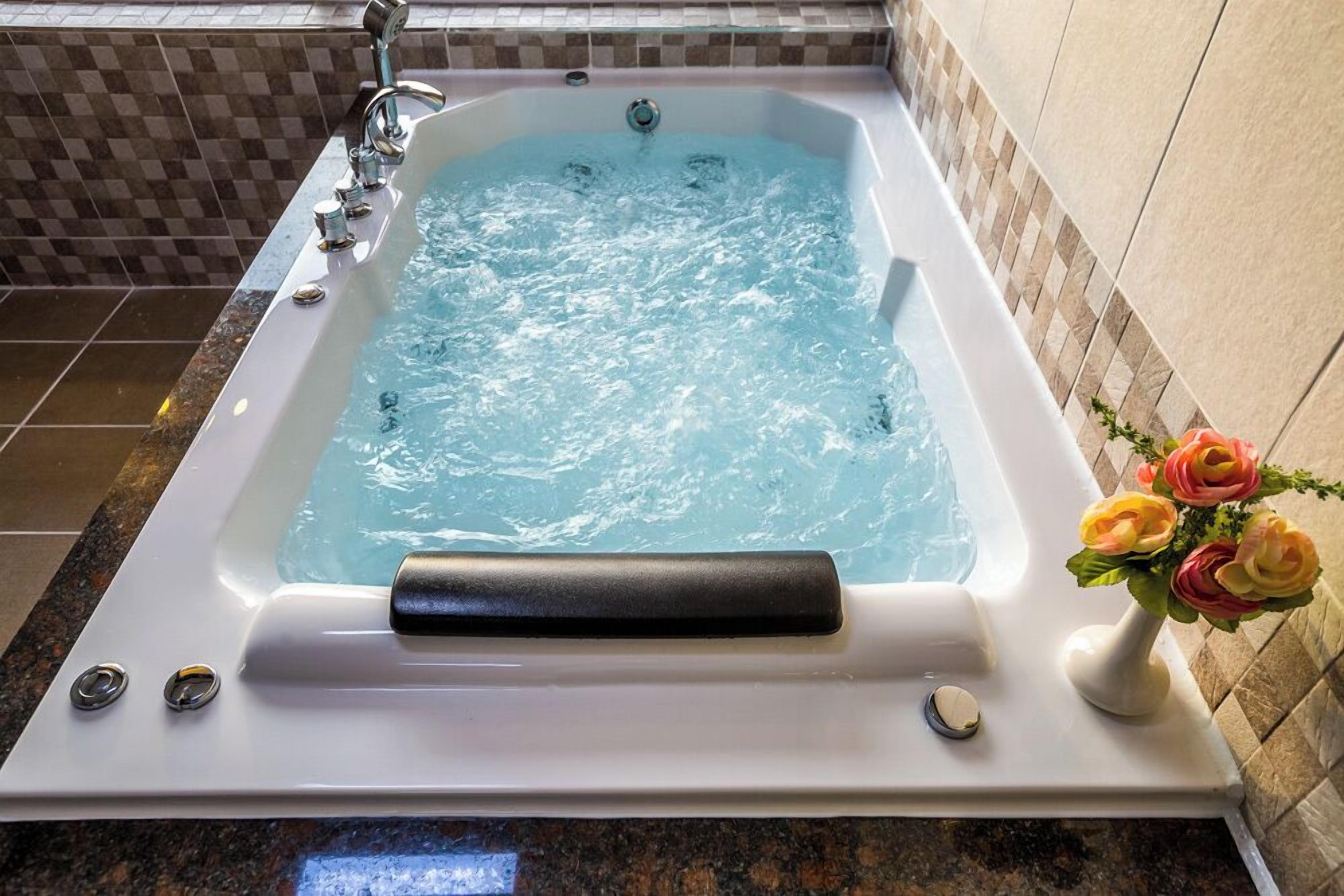 A rectangular hot tub with water jets, a control panel, and a decorative vase with flowers.