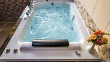 A rectangular hot tub with water jets, a control panel, and a decorative vase with flowers.