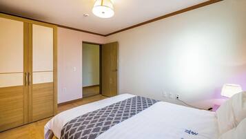 A hotel room with a bed, a wardrobe, a bedside table with a lamp, and a ceiling light.