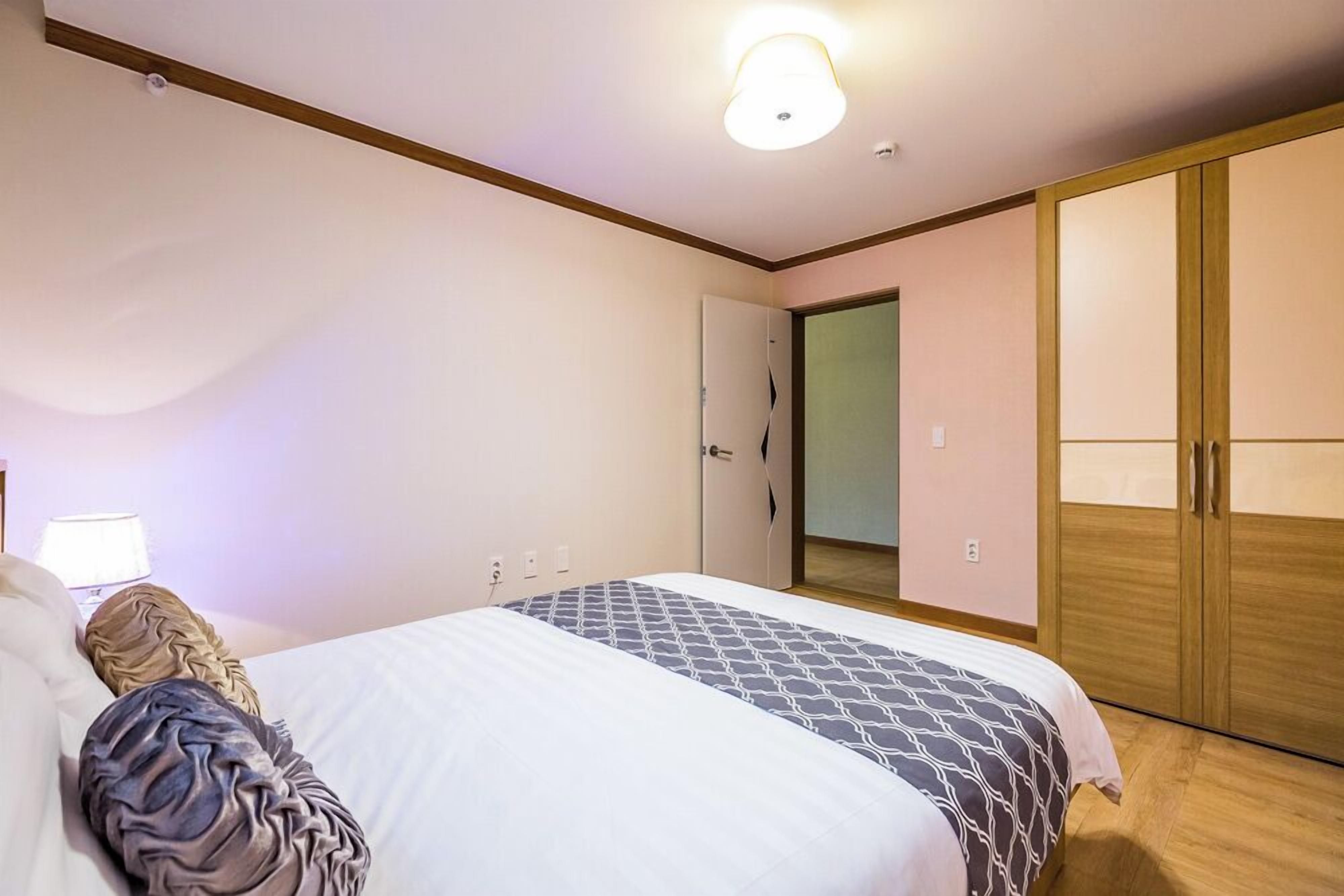 A bedroom with a bed, a wardrobe, and a door.