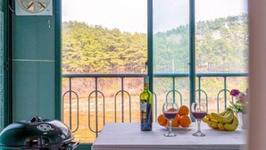Un balcón con una parrilla, una botella de vino, copas y fruta.