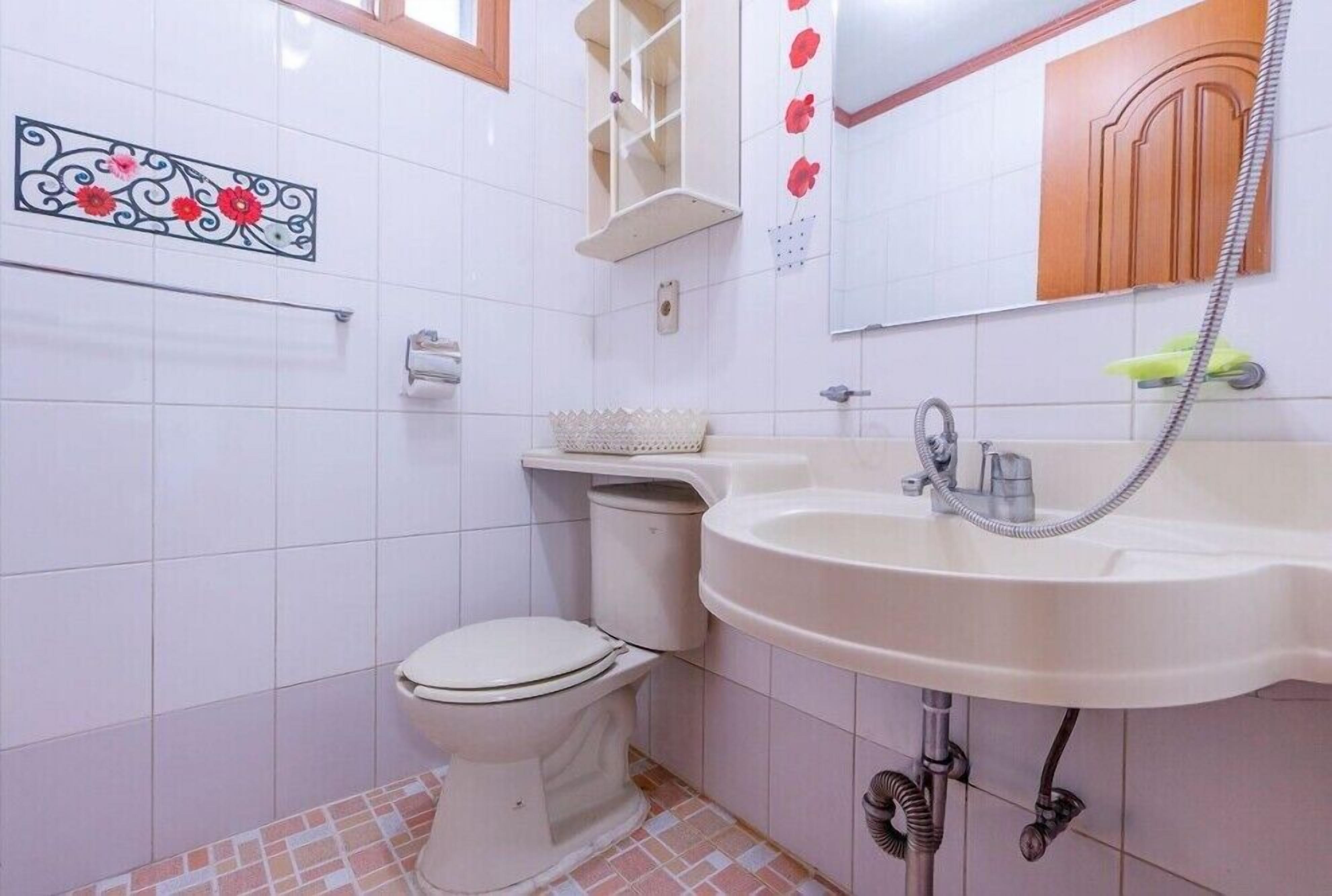 A bathroom with a toilet, sink, and mirror.