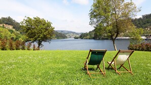 A grassy area with two green folding chairs facing a lake.
