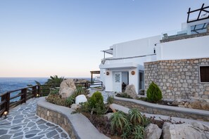 Un edificio moderno con fachada de piedra, terraza de madera y vista al mar.