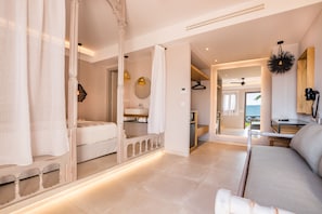 A modern hotel room with a large bed, a sitting area, and a bathroom with a mirror and sink.
