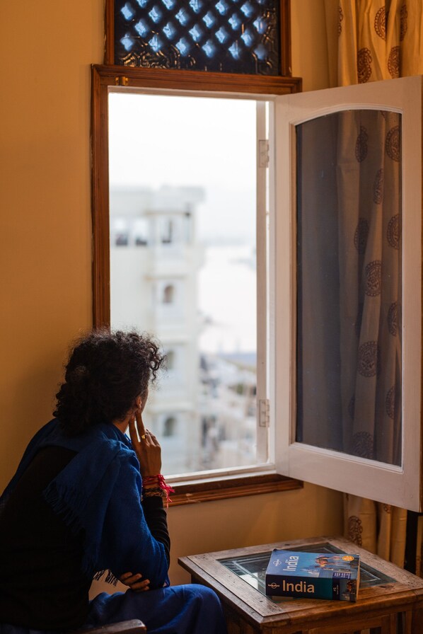 Una persona sentada junto a una ventana con vista a edificios.