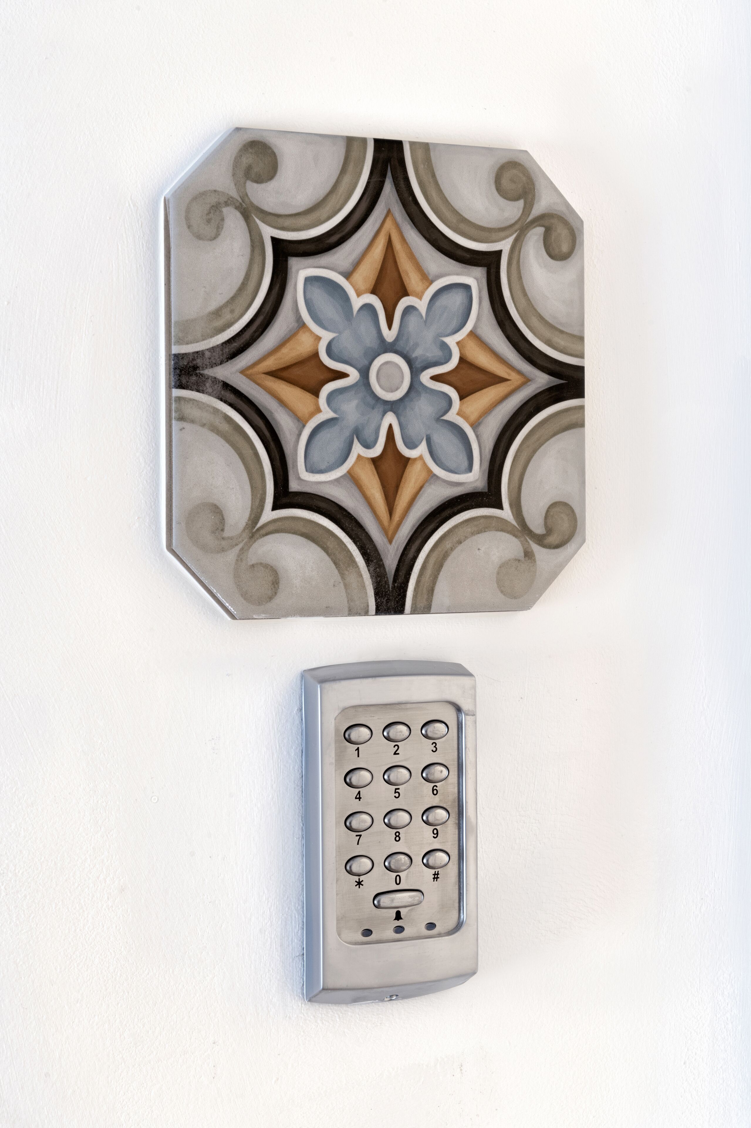 A wall-mounted keypad and decorative tile with a geometric pattern.