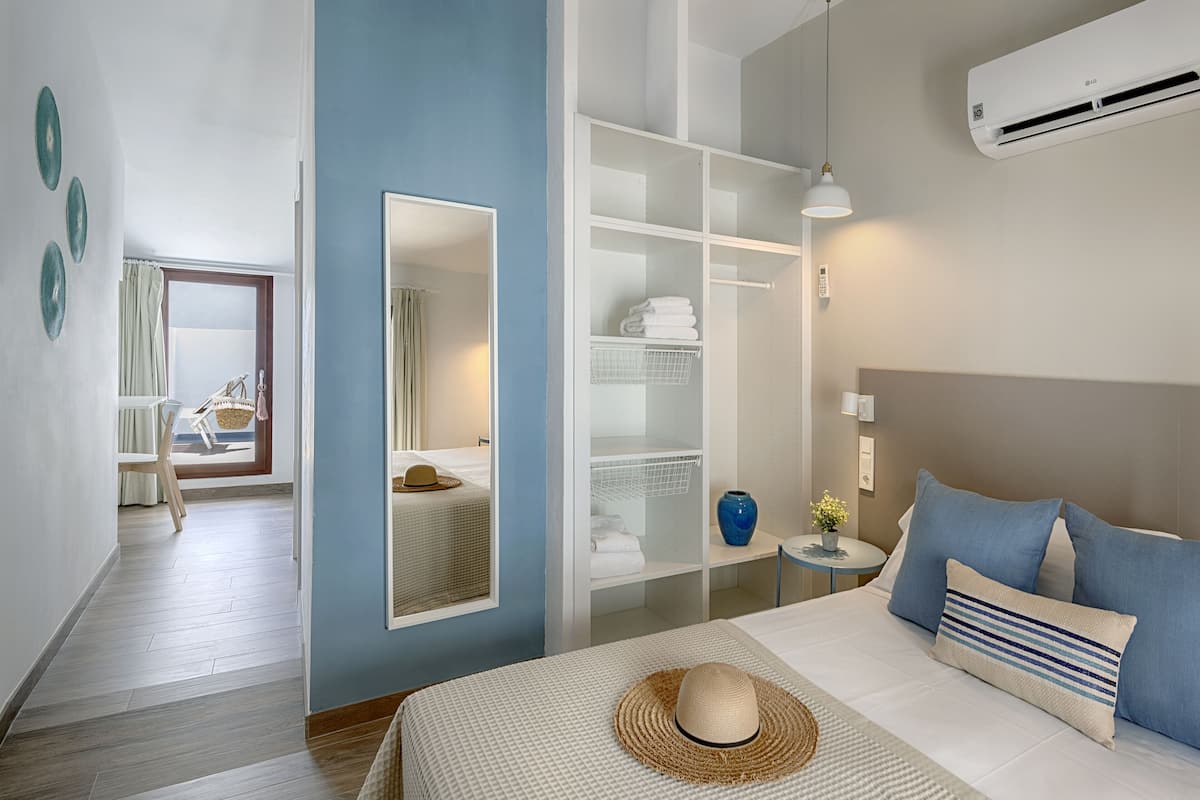 Habitació d'hotel moderna amb un llit, un armari, un mirall i un bany amb barra de tovalloles.