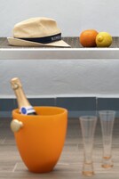 Un chapeau, deux oranges, un citron et un saladier orange contenant une bouteille de champagne.