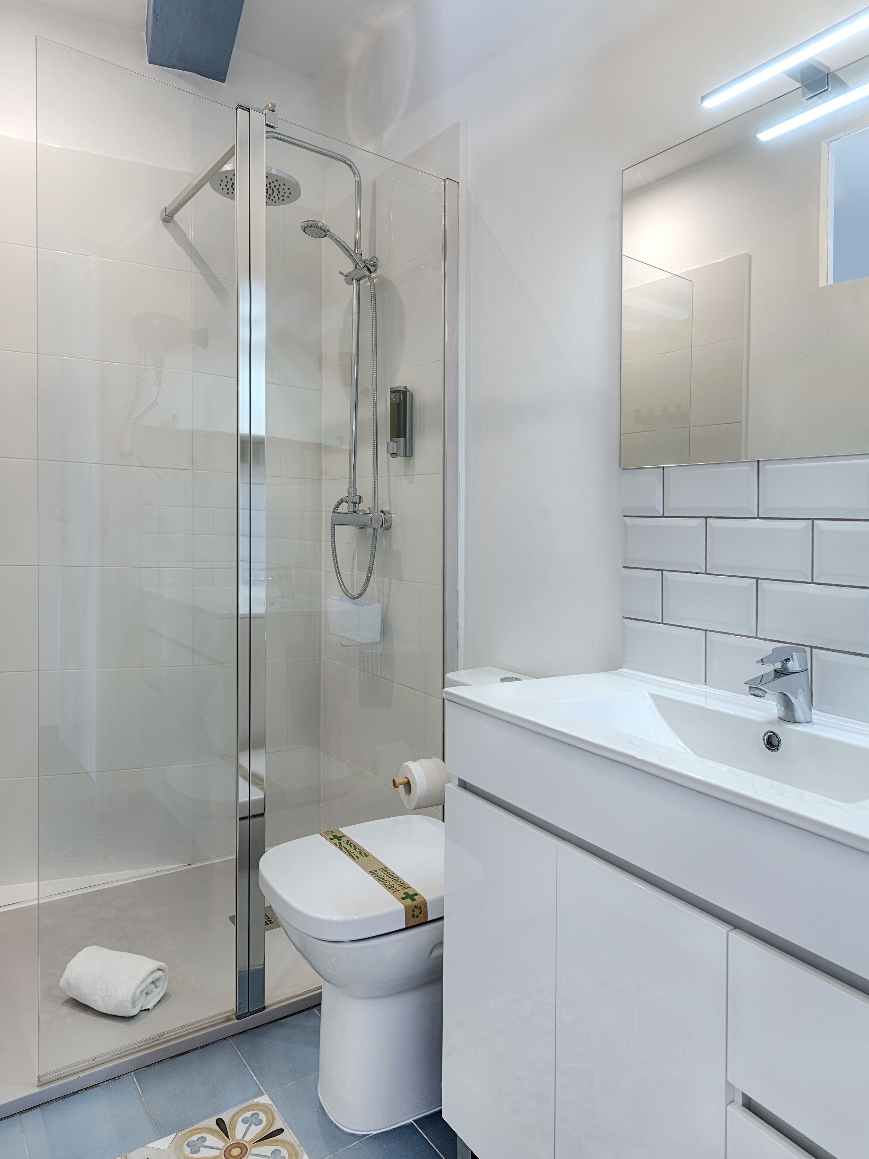 Een moderne badkamer met een douchecabine van glas, een toilet en een wastafel met een spiegel erboven.