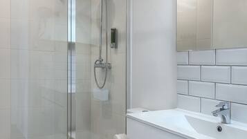 Een moderne badkamer met een douchecabine van glas, een toilet en een wastafel met een spiegel erboven.