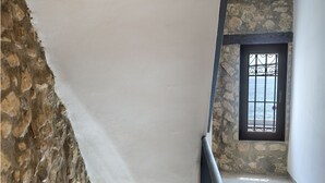 A staircase with stone walls and metal railings, leading to a landing with a view of the sea. - Hostal Altea House (Altea)