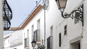 A narrow cobblestone street flanked by white buildings with black wrought iron balconies and ornate street lamps. - Hostal Altea House (Altea)