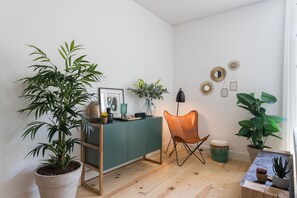 Cozy living space with a green accent wall, wooden floor, and lush plants.