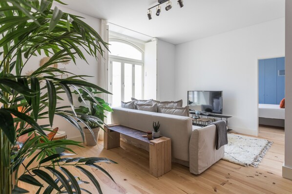 Relax in this stylish living room with a sofa set, flat-screen TV, and potted plants.
