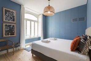 Relax in this serene bedroom with a large bed, framed artworks, and a stylish pendant light.