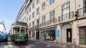 A tram on a street with buildings, including a shop with a sign that says 'MERCADO'.