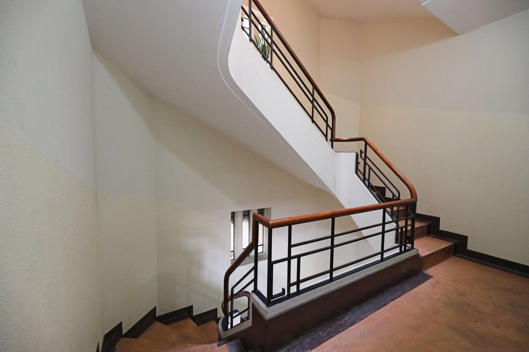 A staircase with a wooden handrail and metal balusters, leading to an upper floor.