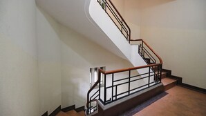 Una escalera con barandilla de madera y balaustradas de metal que conduce a un piso superior.