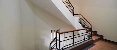 A staircase with a wooden handrail and metal balusters, leading to an upper floor.