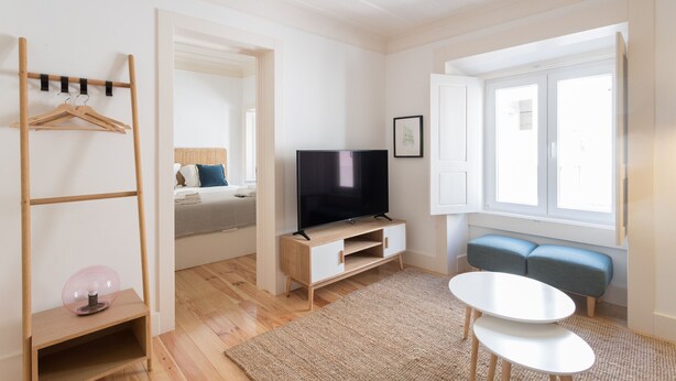 A modern living room with a TV, a sofa, a coffee table, and a wooden coat rack.