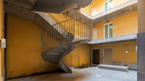 Ein mehrgeschossiges Gebäude mit einer Wendeltreppe, einem Innenhof und einer gelben Fassade.