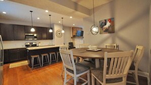 Une cuisine moderne avec des meubles de couleur sombre, un îlot central et des luminaires suspendus.