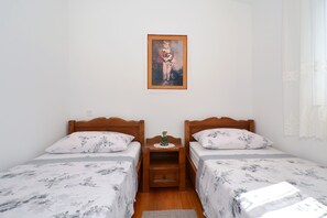 A bedroom with two single beds, a nightstand, a small decorative item, and a framed painting on the wall.