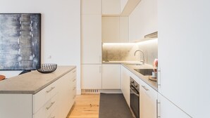 Eine moderne Küche mit weißen Schränken, einer großen Kücheninsel mit Drahtkorb, einer Spüle und einem Herd.
