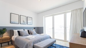 Ein modernes Schlafzimmer mit Bett, Bank und Kunstwerk an der Wand.