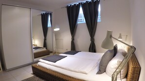 Ett modernt sovrum med en stor säng, ett sängbord, en lampa och en spegel.