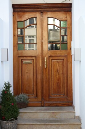 A wooden double door with glass panels and a small basket with plants on the steps. - Modern and spacious vacation apartment for families or couples with a dog (Norderney)